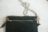 Black suede back of the bag with a silver metal zipper and chain.
