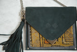 Dark green suede flap with logo, metal corner, and yellow-orange Caucasian rug fragment.