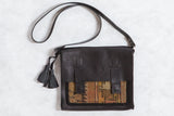 Antique Caucasian rug fragment messenger bag in black leather with orange and yellow geometric details.