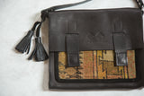 Embossed logo on the pebbled leather flap of the antique Caucasian rug messenger bag.