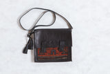 Dark leather messenger bag with a geometric antique Kurdish rug fragment in rust and blue.