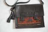 Textured black leather flap with an embossed logo and strap detail on a Kurdish rug bag.