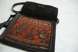 Kurdish rug messenger bag opened to reveal a black leather flap and magnetic closure.
