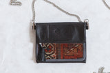 Antique Kurdish rug fragment purse with dark leather, rich earth tones, and tribal pattern.