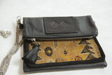 Handbag combining black pebbled leather with an antique Caucasian rug fragment, showing zipper and tassel.