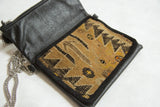 Antique rug bag open, showing the geometric Caucasian fragment and black leather interior.