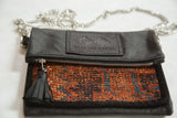 Black leather flap, silver zipper, tassel, and woven antique Kurdish rug fragment texture.