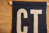 Hand-sewn cream 'CT' felt letters on navy banner, showing oak dowel.