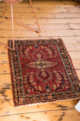 Vintage Sarouk rug featuring a wine red floral bouquet, gold medallion fragment, and navy border.