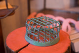 Vintage industrial flower frog with a distressed green caged design.