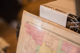 Aged paper of antique NY map, showing faded pink districts and a pinhole.