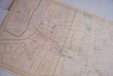 Angled close-up of the antique map's central grid showing colored building plots and streets.