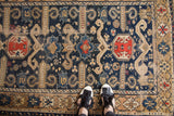 Antique Perpedil rug with distressed navy blue field and ram's horn motifs.