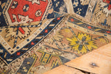 Distressed edge and exposed foundation of an antique Perpedil rug with geometric rams horn motifs.