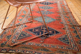 Antique Bijar runner's geometric borders, worn edge, and red field with indigo patterns.
