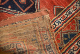 Hand-knotted red and blue geometric pile with visible woven foundation on antique Bijar rug edge.