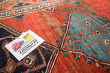 Close-up of antique Bijar rug: cherry red field, blue diamond pattern, visible foundation wear.
