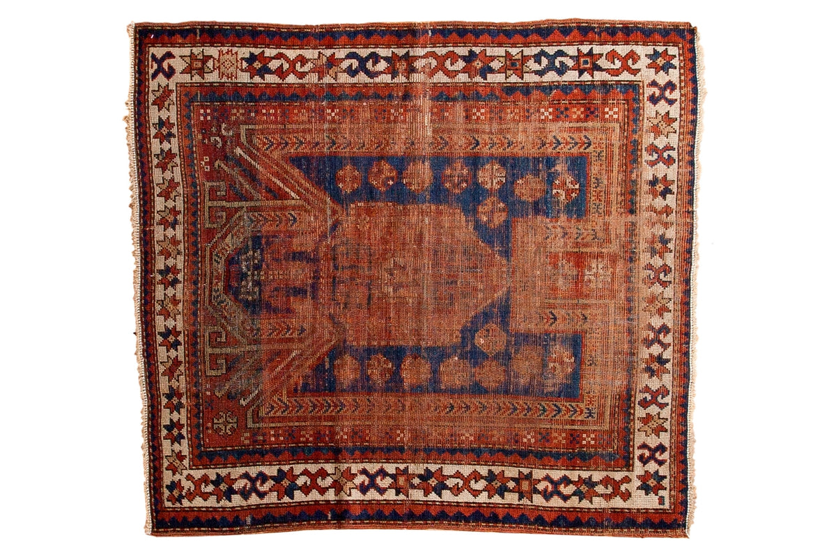Antique Sewan Caucasian square rug with an indigo blue prayer niche and madder root red star and crab border.