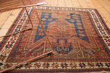 Antique Sewan Caucasian rug: geometric star and crab border, madder red, indigo blue, worn texture.