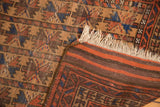 Corner of antique Belouch rug revealing hand-knotted fringe, geometric design, and striped dark back.