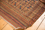 Dog eared corner of antique Belouch rug, showing geometric border and striped kilim.