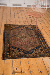 Corner of hand-knotted Dargezine rug, featuring navy blue arabesque spandrel and fringe.