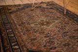 Burnt blush field, Herati motif, and thick navy blue border of the vintage Persian Dargezine rug.