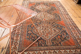 Angled detail of antique Qashqai rug, showcasing madder red medallion and navy field motifs.