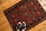 Persian Lilihan rug mat, cherry red floral palmettes, visible texture, tattered sides.