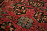 Angled close-up of vintage Lilihan rug pile, showing cherry red field and contrasting floral palmettes.