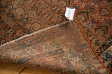 Vintage Hamadan rug corner with intricate plant pattern, woven back, and tattered ends.