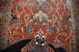Burnt orange field of vintage Mahalati rug showcasing oversized blue palmettes and saffron tendrils.