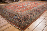 Corner detail of a vintage Persian Mahalati rug, with dark floral palmette borders and tattered fringe.