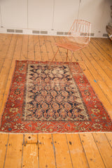 Antique Hamadan rug's madder red border, stylized floral vinery, and tattered ends.