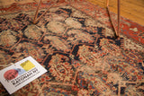 Angled view of antique Hamadan rug field, revealing detailed floral boteh motifs, worn texture, and muted madder red tones.