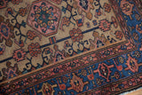 Hand-knotted Persian Hamadan rug showing indigo blue border and beige field plant motifs.