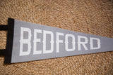 Textured gray felt pennant with prominent white 'BEDFORD' lettering.