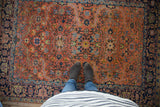 Vintage Heriz rug showcasing curvilinear serrated leaf design in peach and light blue tones underfoot.
