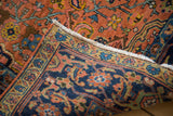 Rich navy blue border featuring intricate floral motifs against the peach field of a vintage Heriz rug.