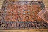 Vintage Heriz rug's deep navy border, curvilinear leaf patterns, and faded peach field.