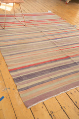 Faded cherry red, mauve, and ivory striped bands on vintage Turkish Kilim carpet edge.