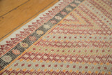 Vintage Turkish jijim carpet's repeating diamond overlay format in red, orange, and ivory.
