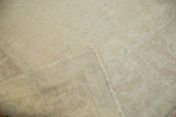 Pale beige Oushak rug pile texture and folded corner revealing hand knotted foundation.