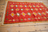 Plush pile with tangerine, ivory, and aqua geometric motifs on vintage Moroccan rug corner.