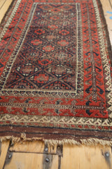 Antique Belouch runner detail: aubergine geometric lattice, tree-of-life border, worn pile.
