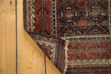 Antique Belouch rug corner revealing hand-knotted backing, dark goat hair selvage, and fringe.