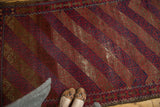 Vintage Belouch rug with diagonal red and indigo geometric bands, showing visible foundation wear.