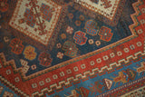Antique Persian Afshar rug close-up: dark indigo field, colorful pomegranate motifs, and rich red borders.