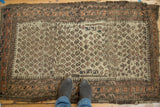 Hand-knotted Belouch rug, heavily worn, with allover boteh motif and rare ivory field.
