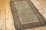 Antique Belouch rug corner with exposed foundation, tattered fringe, ivory boteh field, and geometric border.